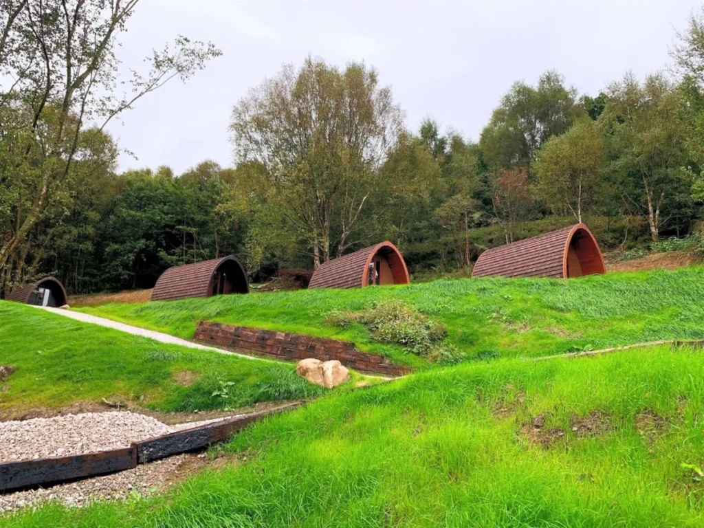 The glamping pods in a row above the camping field, in high summer